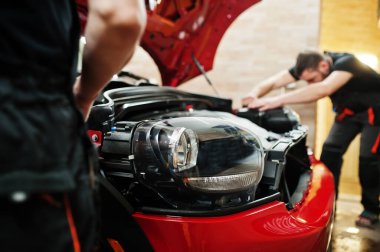 Araba servisi çalışanı, araba tamirhanesindeki kırmızı bir arabanın üzerine çakıl önleyici film koymuş. Özel filmli araba koruması.