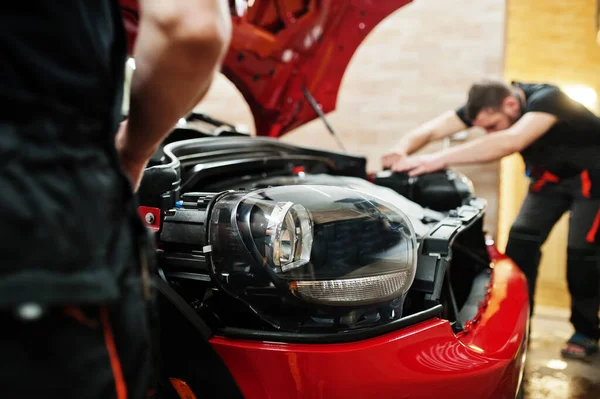 Araba servisi çalışanı, araba tamirhanesindeki kırmızı bir arabanın üzerine çakıl önleyici film koymuş. Özel filmli araba koruması.