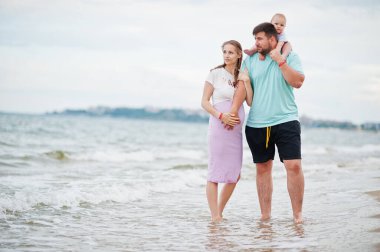 Yaz tatilleri. Ebeveynler ve insanlar çocuklarla birlikte dışarıda faaliyet gösteriyor. Mutlu aile tatilleri. Baba, hamile anne, küçük kız deniz kumsalında.. 