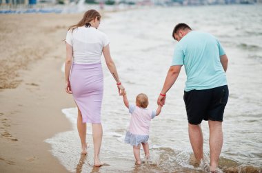 Yaz tatilleri. Ebeveynler ve insanlar çocuklarla birlikte dışarıda faaliyet gösteriyor. Mutlu aile tatilleri. Baba, hamile anne, deniz kumsalındaki küçük kız.. 