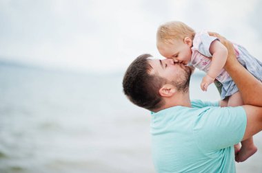 Yaz tatilleri. Ebeveynler ve insanlar çocuklarla birlikte dışarıda faaliyet gösteriyor. Mutlu aile tatilleri. Baba ve kızı deniz kumsalında. 