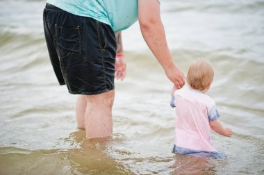 Yaz tatilleri. Ebeveynler ve insanlar çocuklarla birlikte dışarıda faaliyet gösteriyor. Mutlu aile tatilleri. Babası ve küçük kızı denizde..