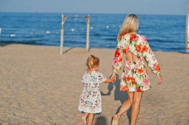 Anne ve güzel kız sahilde eğleniyorlar. Tatilde küçük tatlı bir kızla mutlu bir kadının portresi.. 