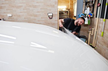 Tamirhanedeki işçiler beyaz lüks arabaya poliüretan anti-çakıl film kapağı koymuşlar..