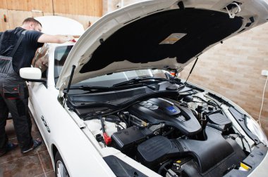 Tamirhanedeki işçiler beyaz lüks arabaya poliüretan anti-çakıl film kapağı koymuşlar..