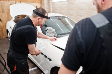 Tamirhanedeki işçiler beyaz lüks arabaya poliüretan anti-çakıl film kapağı koymuşlar..