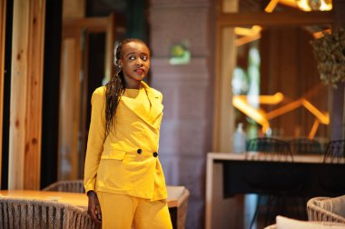 Hoş görünümlü, şık, çekici, hoş, içeriği hoş, neşeli, Afro-Amerikan kızının portresi parlak, parlak, parlak, sarı renkli bir ceket ya da kostüm giyer..