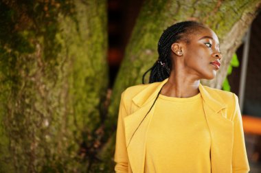 Hoş görünümlü, şık, çekici, hoş, içeriği hoş, neşeli, Afro-Amerikan kızının portresi parlak, parlak, parlak, sarı renkli bir ceket ya da kostüm giyer..