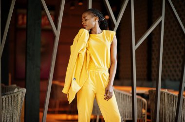 Hoş görünümlü, şık, çekici, hoş, içeriği hoş, neşeli, Afro-Amerikan kızının portresi parlak, parlak, parlak, sarı renkli bir ceket ya da kostüm giyer..