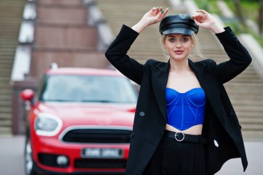 Şapkalı, siyah, mavi korseli, kırmızı şehir arabasının yanında parlak makyajlı güzel, sarışın, seksi kadın modelin portresi.. 