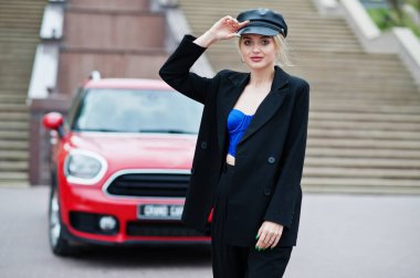 Şapkalı, siyah, mavi korseli, kırmızı şehir arabasının yanında parlak makyajlı güzel, sarışın, seksi kadın modelin portresi.. 