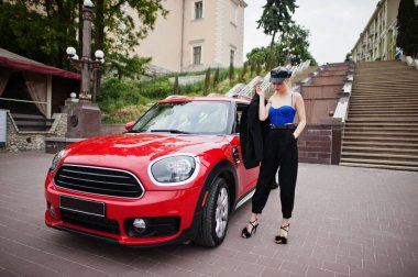 Kırmızı şehir arabasının yanında siyah makyajlı ve şapkalı güzel sarışın seksi model portresi.. 