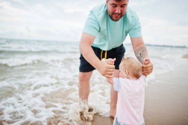 Yaz tatilleri. Ebeveynler ve insanlar çocuklarla birlikte dışarıda faaliyet gösteriyor. Mutlu aile tatilleri. Baba ve kızı deniz kumsalında. 
