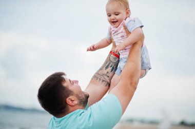 Yaz tatilleri. Ebeveynler ve insanlar çocuklarla birlikte dışarıda faaliyet gösteriyor. Mutlu aile tatilleri. Baba ve kızı deniz kumsalında. 