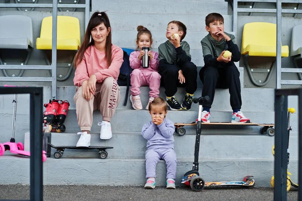 Joven Madre Elegante Con Cuatro Niños Sentados Podio Deportivo Estadio — Foto de Stock