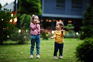 Akşam bahçesinde donutları olan iki kız kardeş. Lezzetli donut yemeği..