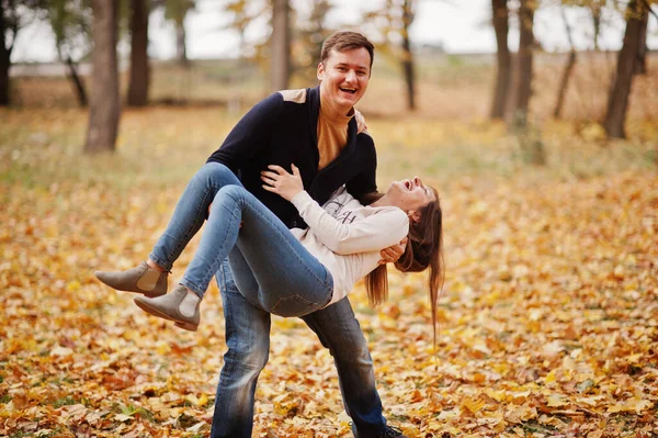 秋の紅葉公園で素敵なカップル 夫は妻を抱きかかえて — ストック写真