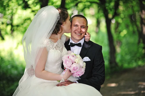 Свадебная пара целуется в зеленом парке — стоковое фото