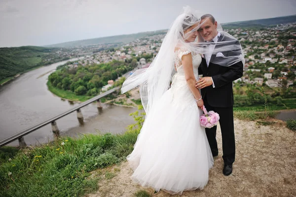 Matrimonio coppia soggiorno su una collina vicino al fiume e ponte — Foto Stock