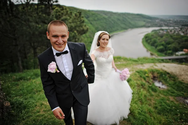 Couple de mariage marcher sur une colline près de la rivière et le pont — Photo