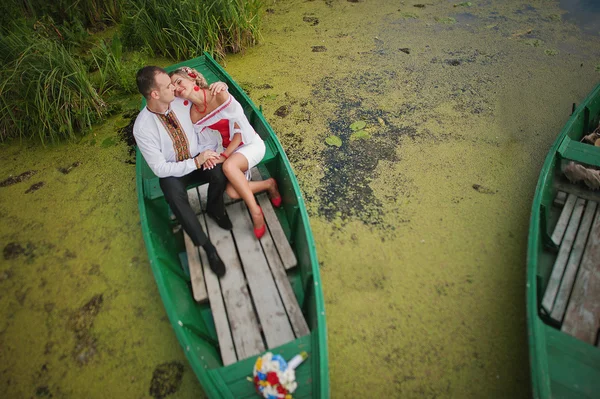 Wedding beautiful couple in traditional dress on the dock sittin — Stock Photo, Image