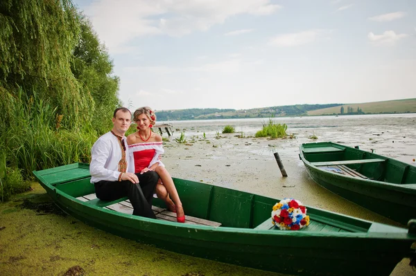 Wedding beautiful couple in traditional dress on the dock sittin — Stock Photo, Image