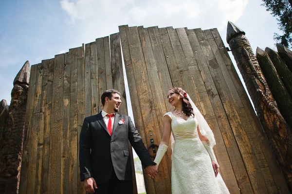 Couple de mariage près de vieille clôture en bois tenant la main — Photo