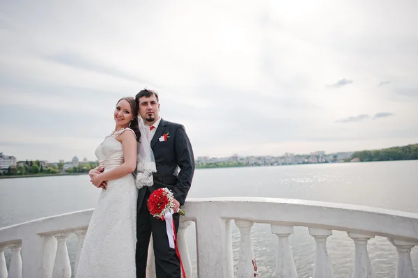 Svatební pár na mostě u jezera — Stock fotografie
