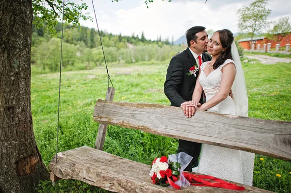 Свадебная пара возле деревянных качелей — стоковое фото