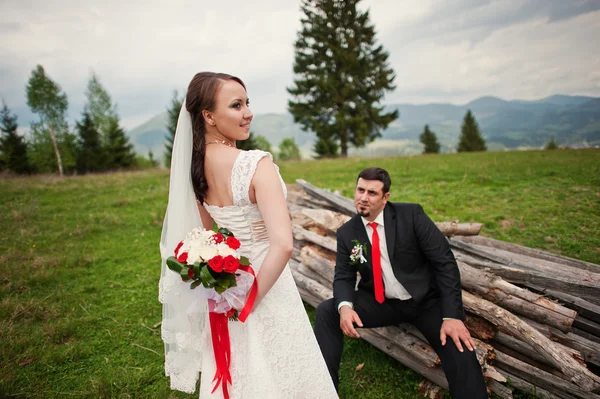 Wedding couple in the Carpathian Mountains. Groom sits on the bo — Stock Photo, Image