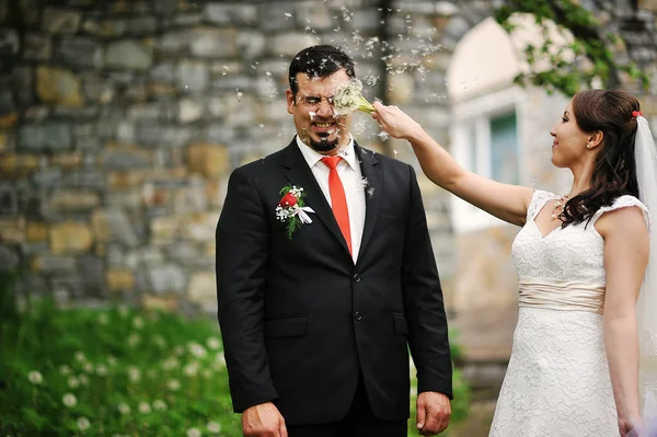 Wedding couple blowing on a dandelion — Stock Photo, Image