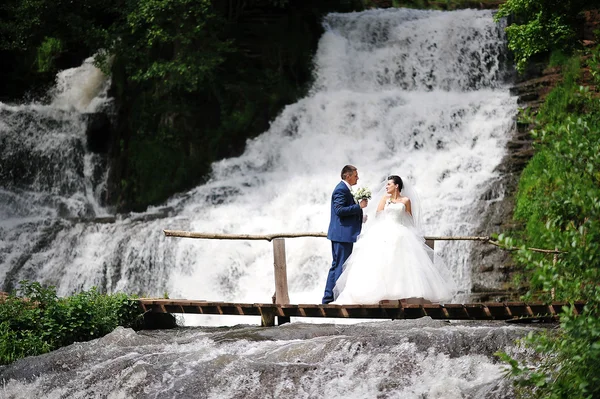 Beautiful wedding couple near waterfall — Stock Photo, Image