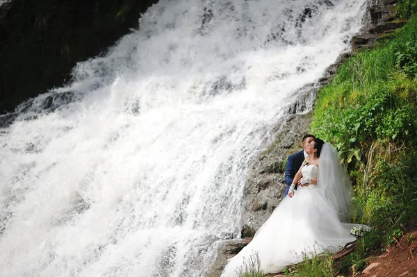 Beautiful wedding couple near waterfall — Stock Photo, Image
