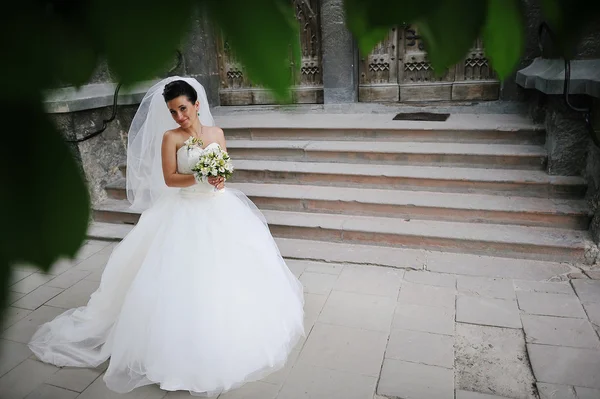 Невеста с букетом рядом с лестницей старой церкви — стоковое фото