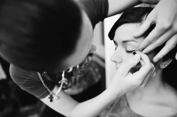 Giovane sposa bruna che applica il trucco nuziale da make-up artist — Foto Stock