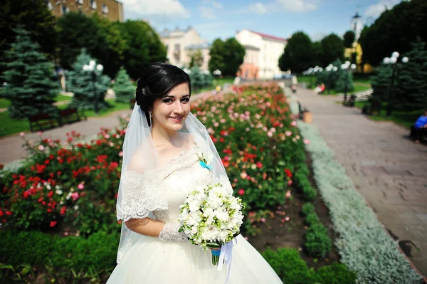 Брюнетка невеста с букетом возле цветов — стоковое фото