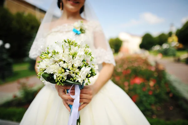 Morena novia con ramo cerca de las flores — Foto de Stock