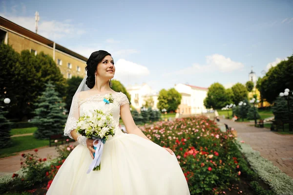 Brunette bride with bouquet near the flowers — Stock Photo, Image