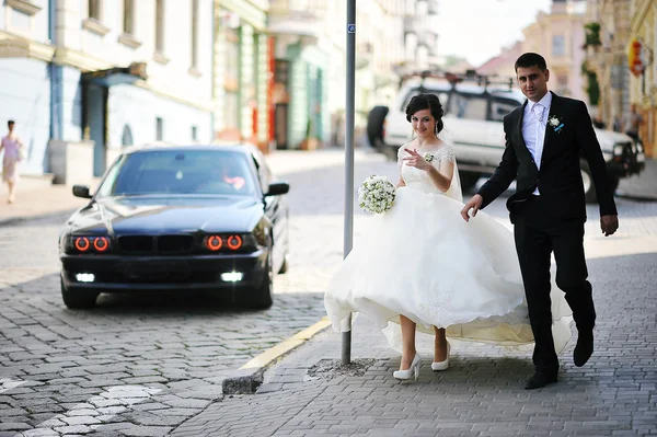 Caminar recién casados en backqround coche negro —  Fotos de Stock