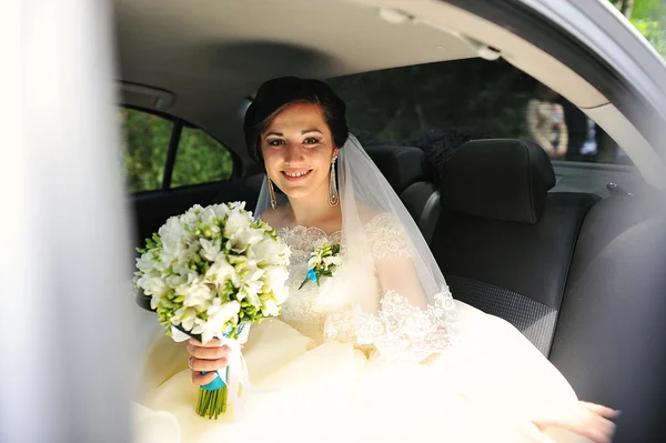 Fiatal szép mosolygó menyasszony csokor ül az autóban — Stock Fotó