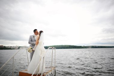 Düğün çift rüzgarlı hava kucaklama üzerinde göl yakınındaki