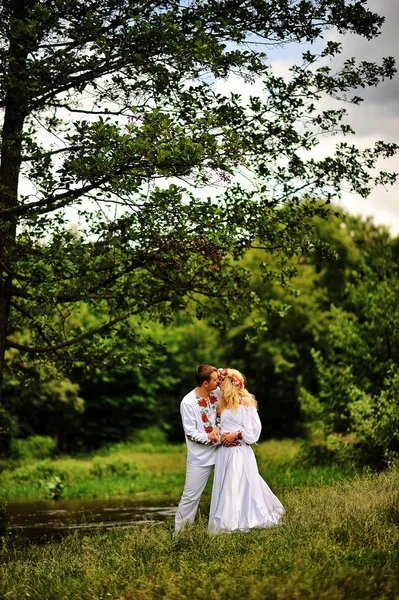 Jovem belo casal em vestido tradicional sob a árvore — Fotografia de Stock