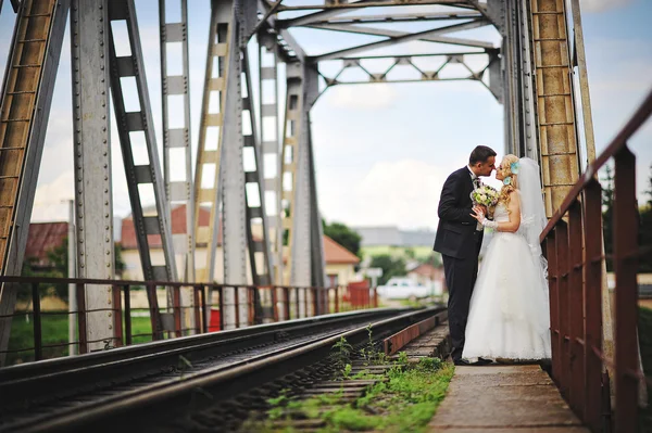 Joven hermosa pareja de boda en el puente del tren —  Fotos de Stock