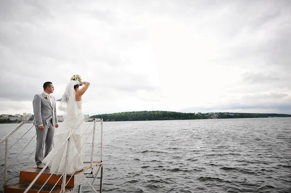 Matrimonio coppia sul tempo ventoso abbraccio vicino al lago — Foto Stock