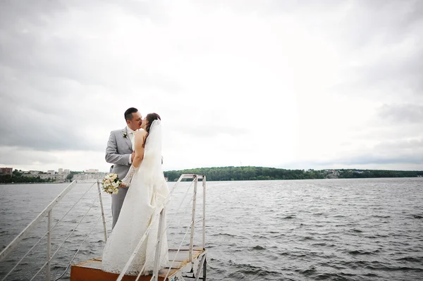 Düğün çift rüzgarlı hava kucaklama üzerinde göl yakınındaki