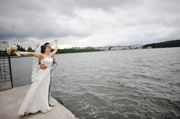 Matrimonio coppia sul tempo ventoso abbraccio vicino al lago — Foto Stock