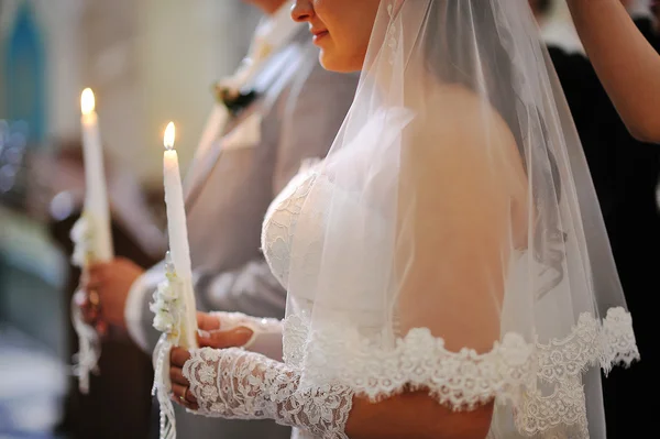 Candles at hads of newlyweds on church — Stock Photo, Image