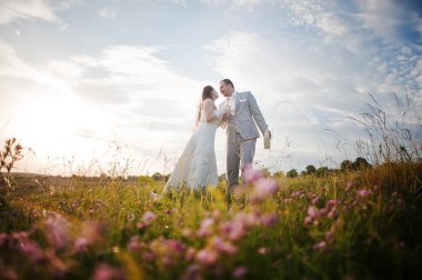 Çiçekli günbatımı üzerinde yeni evliler 