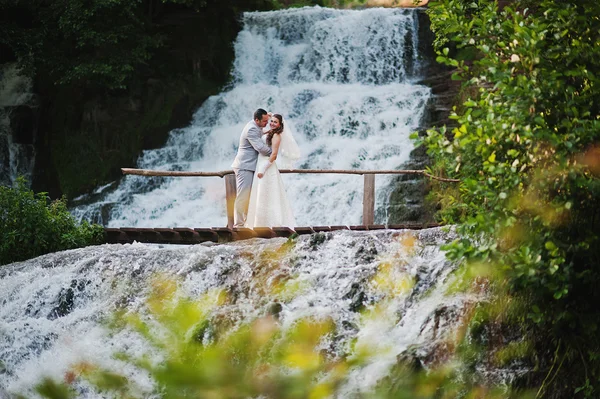 Heureux jeunes mariés près de la cascade — Photo