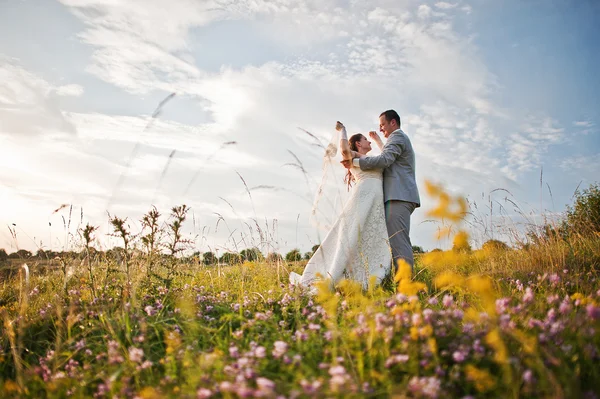 Çiçekli günbatımı üzerinde yeni evliler — Stok fotoğraf